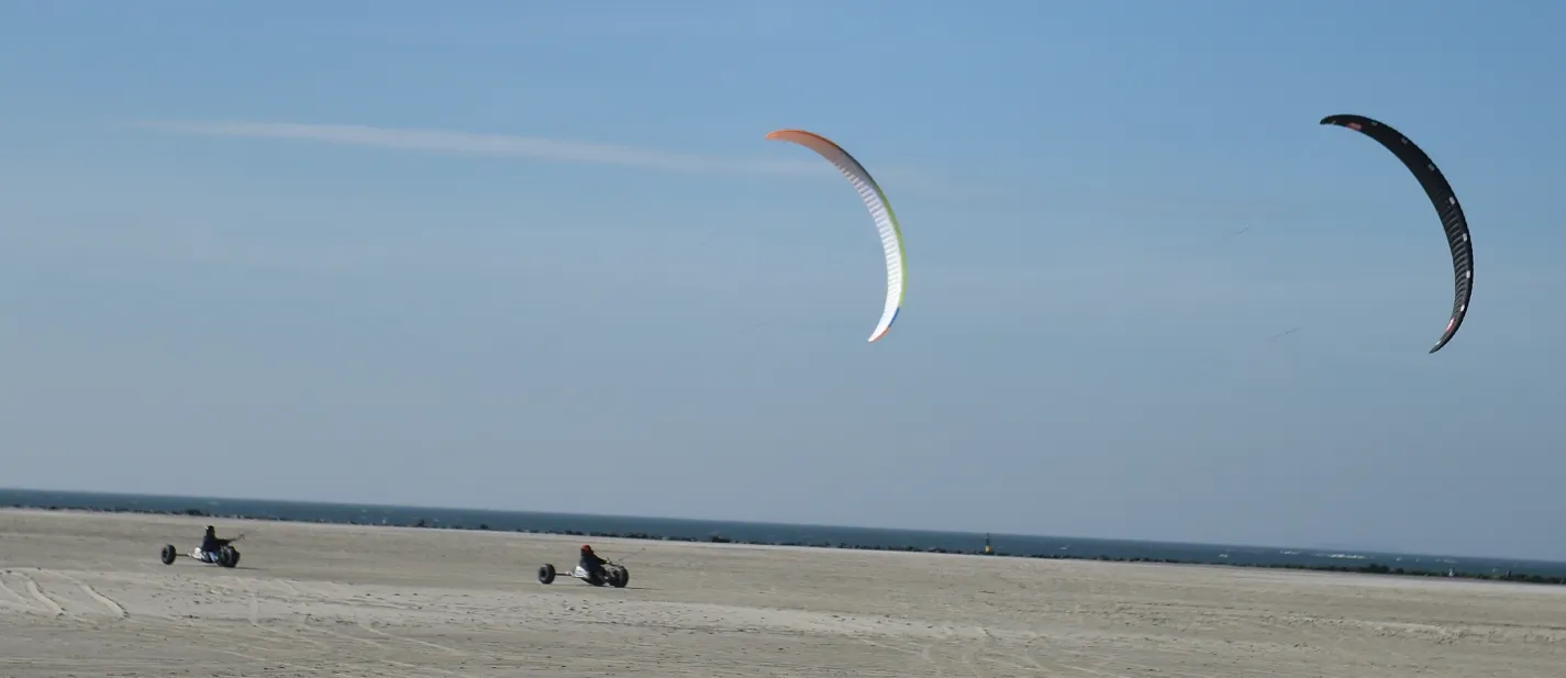 Twee kitebuggy's met kites op het strand bij de zee