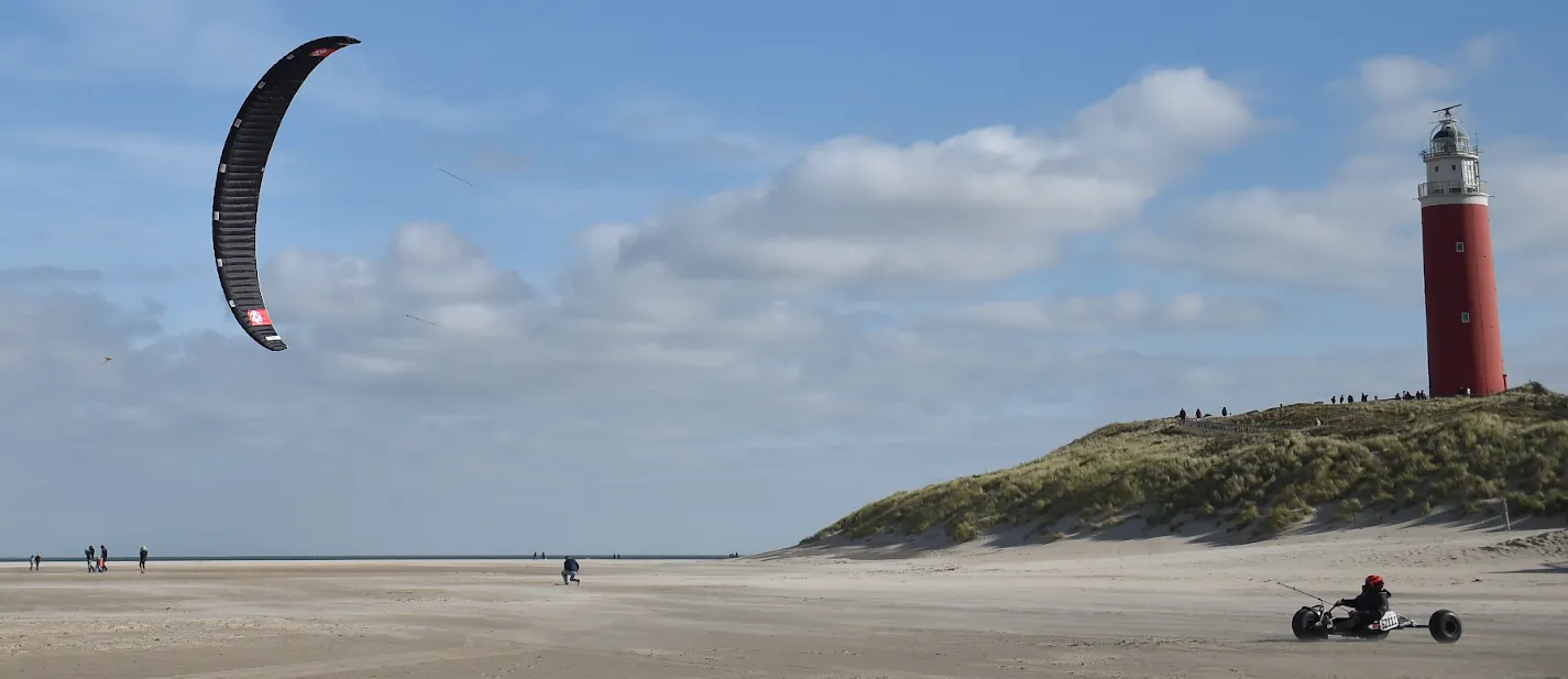 Kitebuggy rijdt langs het duin met de rode vuurtoren