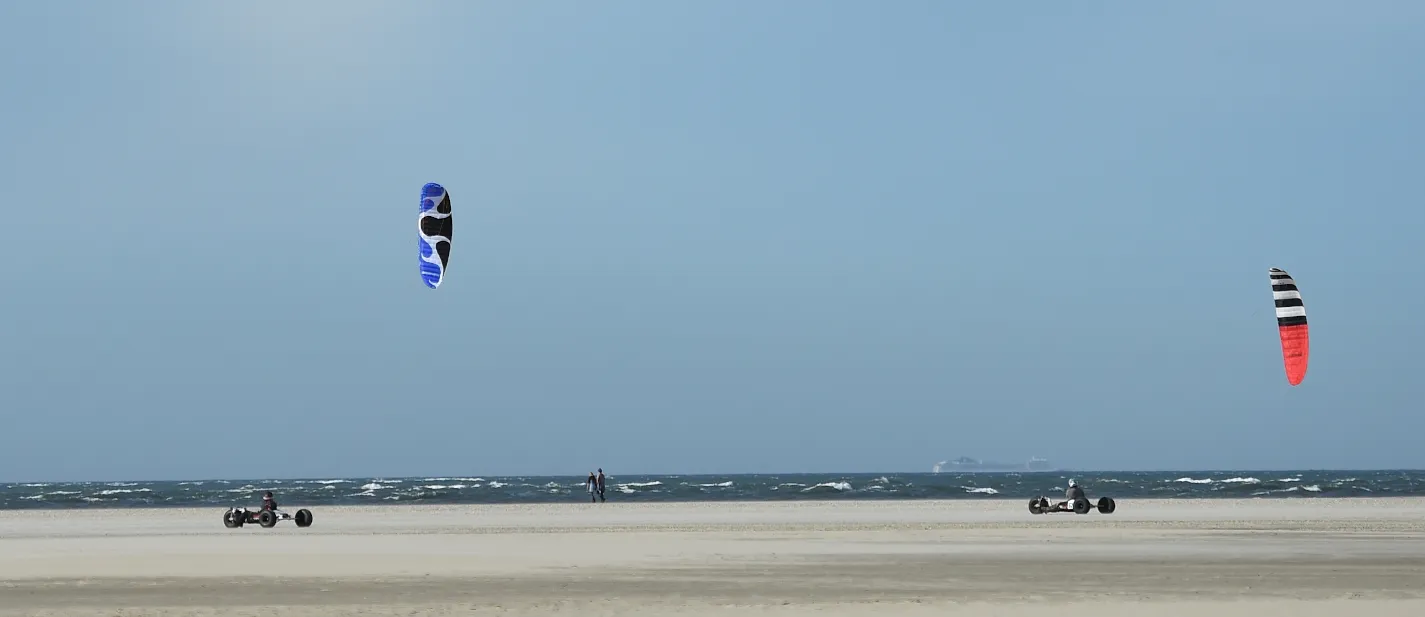 Twee kitebuggy's met een blauwe en een rood-witte kite